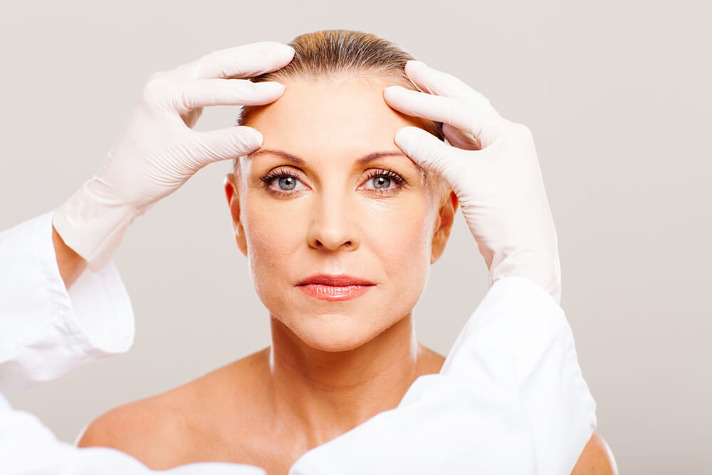 Doctor lifting up eyebrows of beautiful woman